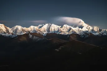 雪覆盖的山脉 阳光和云彩照耀