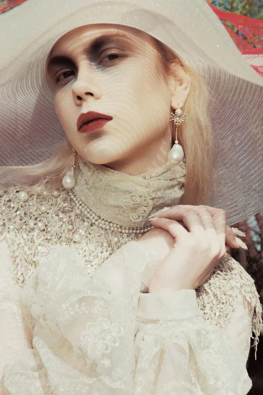 一个人在模特身上穿着一件带有珍珠的白裙子和小礼帽
