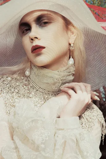 一个人在模特身上穿着一件带有珍珠的白裙子和小礼帽