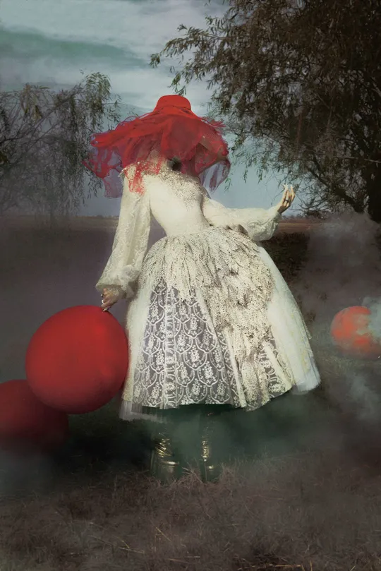 一幅女士穿着白色连衣裙和红色帽子上有红色球的画