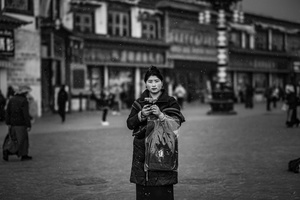 一张黑白照片 一个人拿着一个包在街上走。