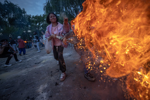 一个小女孩向街道上的大型篝火扔火。
