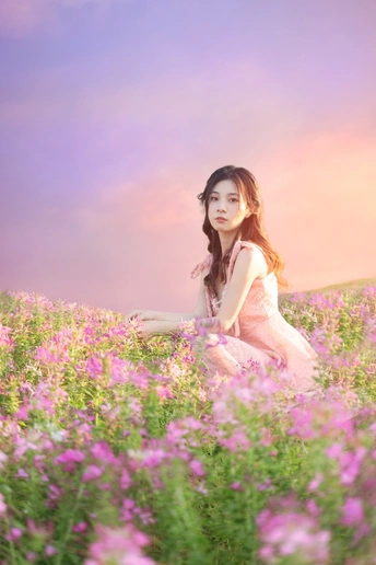 美丽的年轻女子穿着粉红色裙子坐在紫花丛中