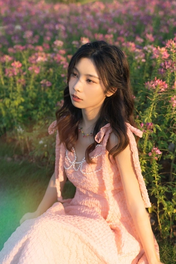 一个穿着粉红色裙子的美丽年轻女子坐在花丛中