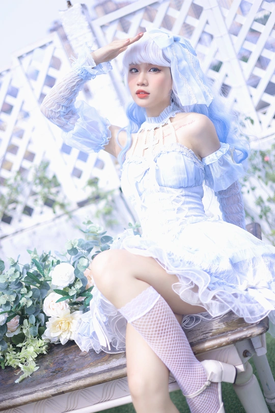 一个穿着白色连衣裙的女人坐在鲜花旁边的木长椅上