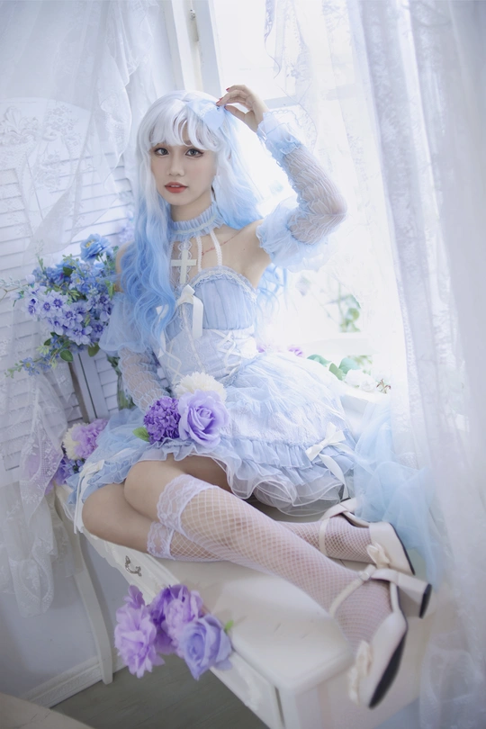 一个蓝色头发和白色连衣裙的娃娃坐在窗前的白色椅子上