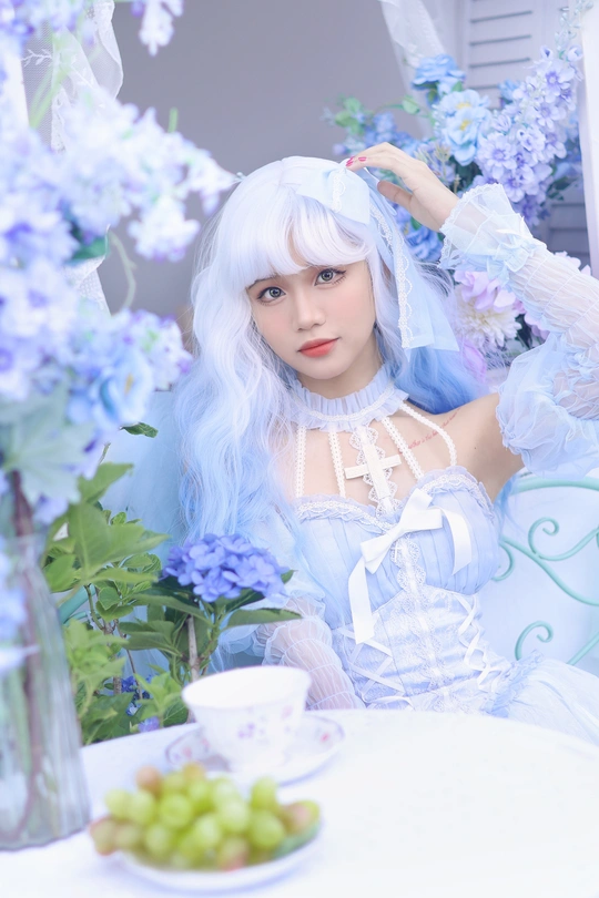 坐在桌子旁的一个蓝色头发、穿着白色连衣裙的女人