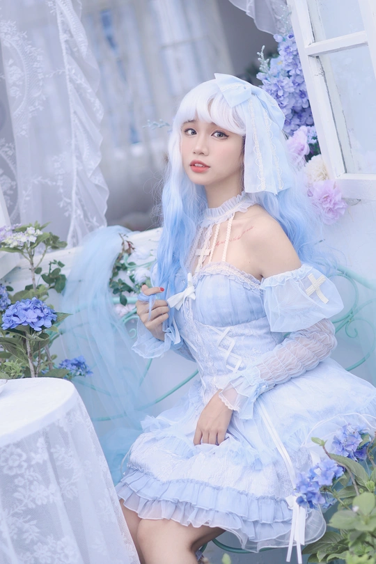 坐在鲜花旁边的一个蓝色头发、穿着白色连衣裙的女人