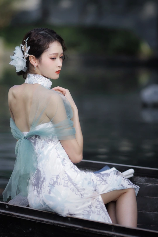 一位穿着白色连衣裙的美丽年轻女士坐在水中的船上