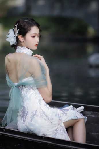 一位穿着白色连衣裙的美丽年轻女士坐在水中的船上