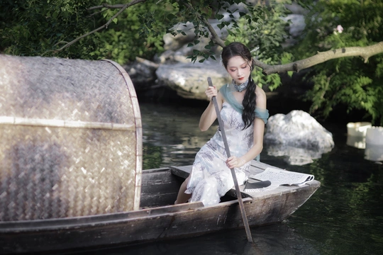 一个穿着白色衣服的年轻女子划着小船顺流而下