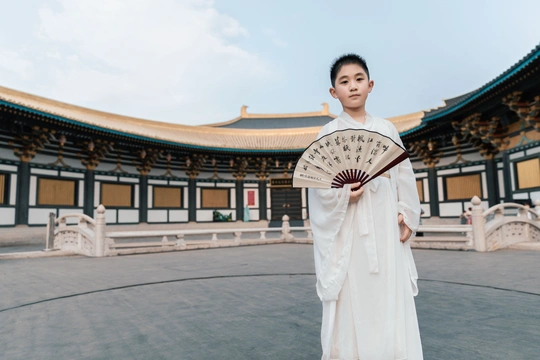 一位身穿传统白色和服的年轻女子手持扇子站在一栋大楼前