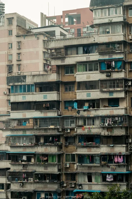 许多窗户的摩天大楼 在大城市的街道上 人们聚集在前面。