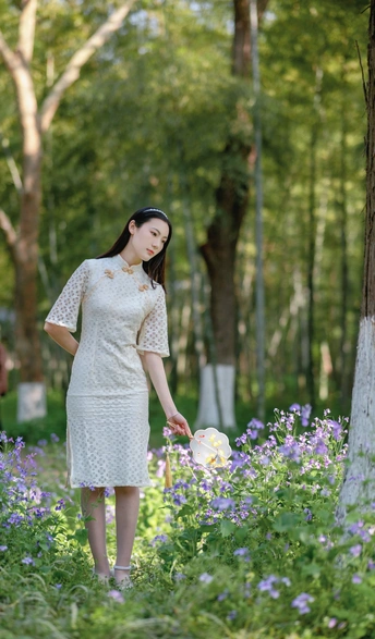 一个穿着白色连衣裙的年轻女子站在一片紫花丛中