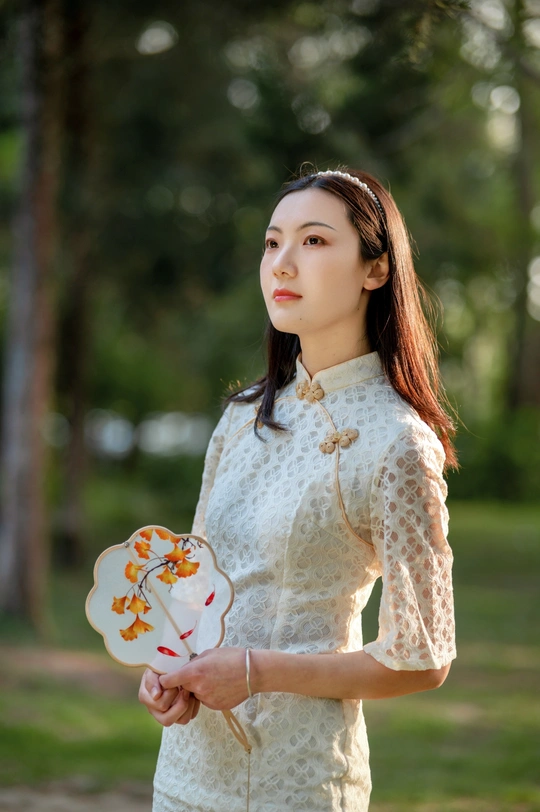 一位年轻女子穿着白色连衣裙 手里拿着一朵花。