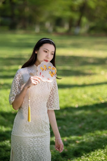 一位穿着白色连衣裙的年轻女子手里拿着一把花伞