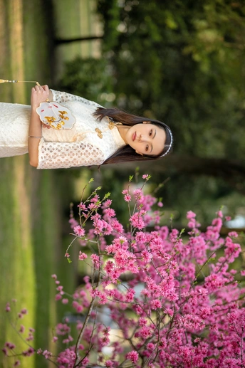 一位穿着白色连衣裙的年轻女子手持雨伞摆姿势拍照