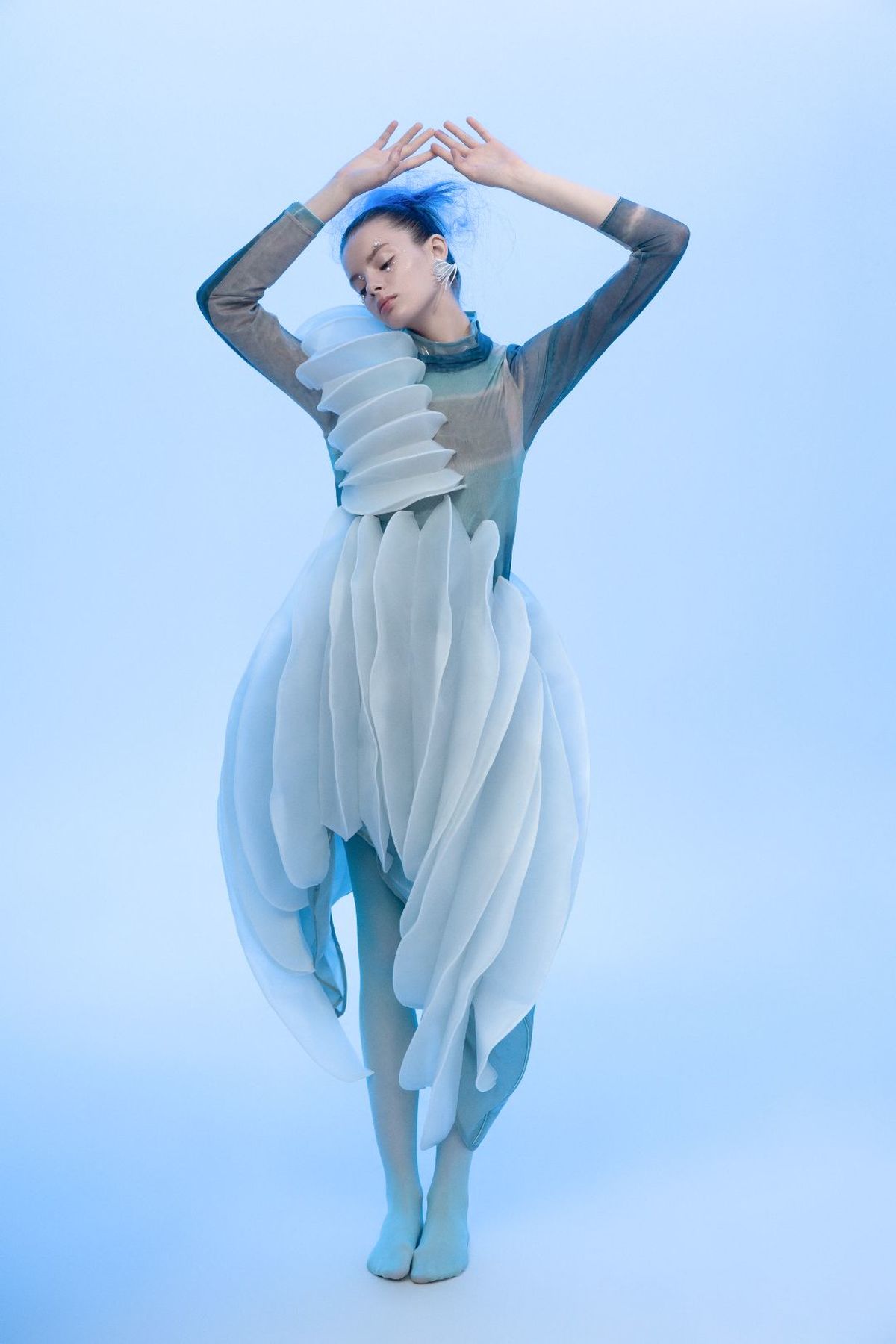 一位戴蓝发、穿白裙子的女子在蓝色背景上跳舞