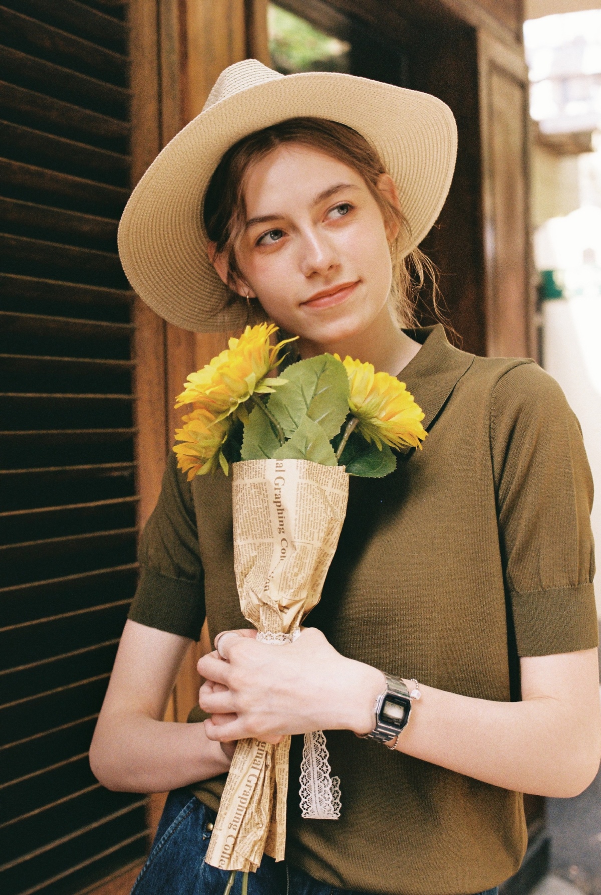 一位戴帽子的小姐拿着一束黄色的花