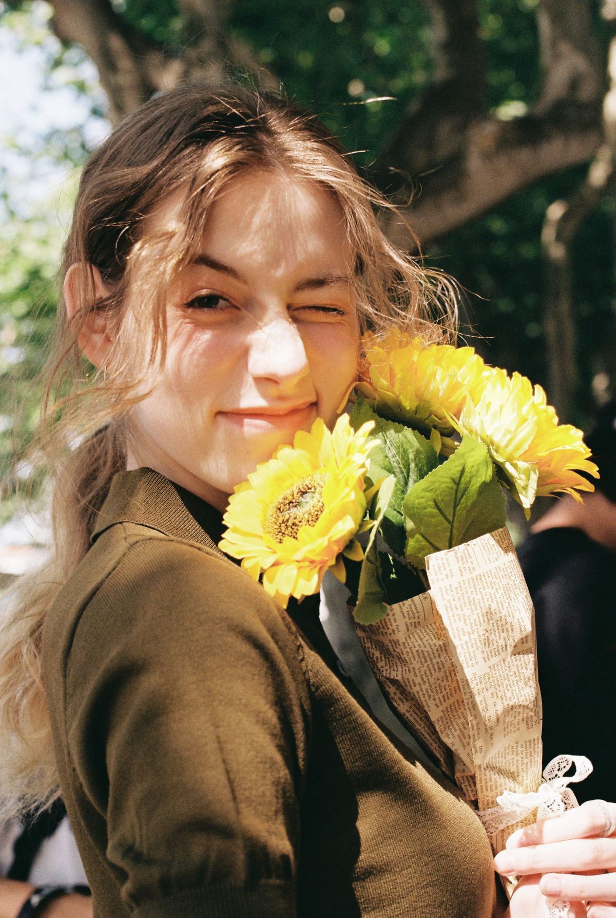 一位年轻女子举着向日葵花束对着她的脸