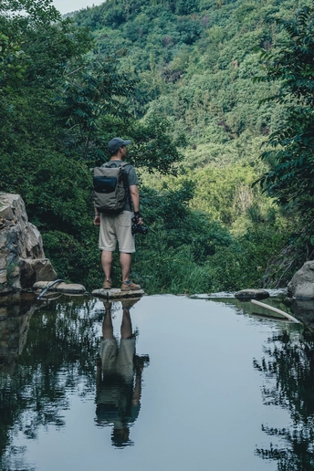 一个背着背包的男人站在一条河或溪流上的桥上