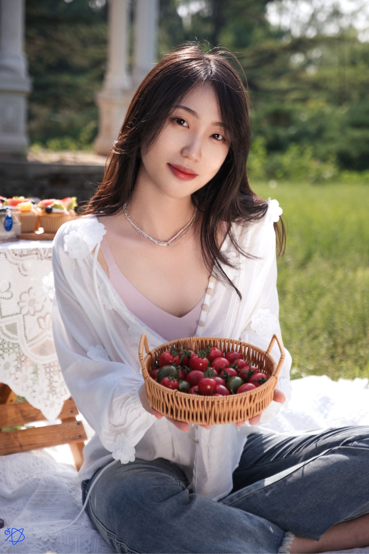 一位美丽的女士在野餐时拿着一个装满红樱桃和苹果的篮子。