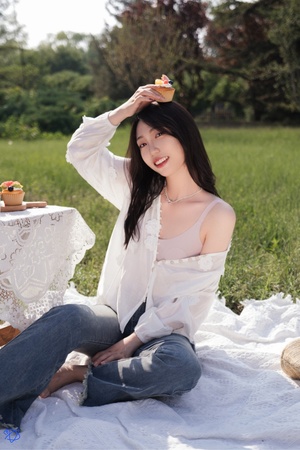 一个穿着白衬衫的年轻女子坐在草地上 头上有食物。