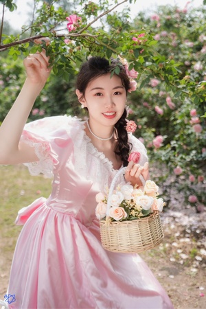 美丽的年轻女子穿着粉色裙子 手里拿着一个装满花的篮子。