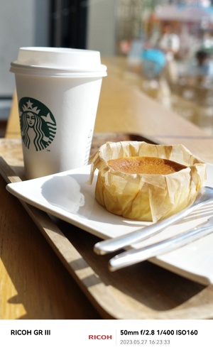 一个带有甜点的白盘子 放在一个木托盘上 旁边放着一杯咖啡。