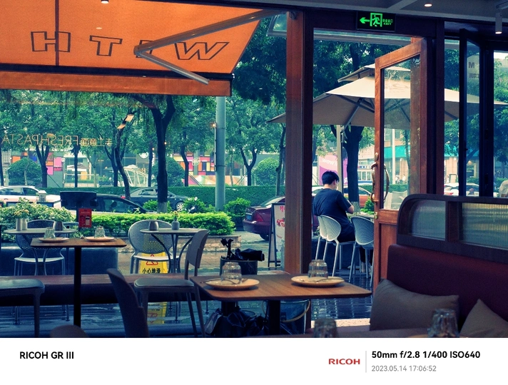 一个人坐在餐馆外面的桌子旁