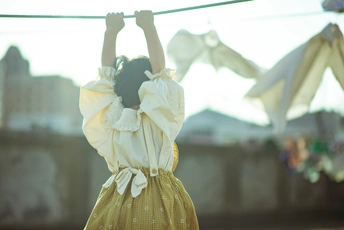 一个穿着黄色连衣裙的年轻女子把洗好的衣服挂在绳子上
