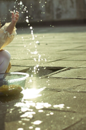 一个小女孩坐在地板上玩喷泉里的一小碗水