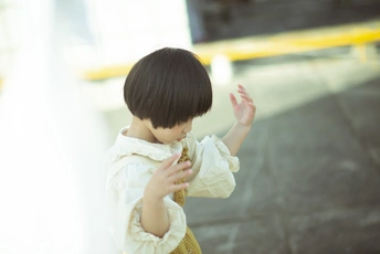 一个穿着白色衣服的小女孩把手伸到一把小伞前