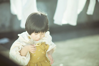 一个穿着黄色连衣裙的小女孩在玩衣服