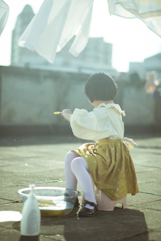 一个穿着裙子的小女孩在屋顶上玩一个小碗