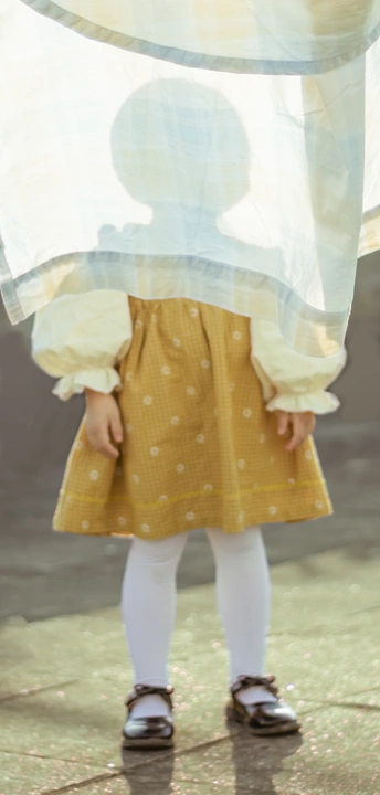 一个穿着黄色连衣裙、打着白色雨伞的小孩