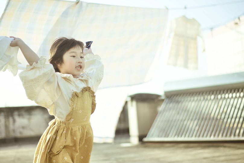 一个穿着白色连衣裙的小女孩站在伞下