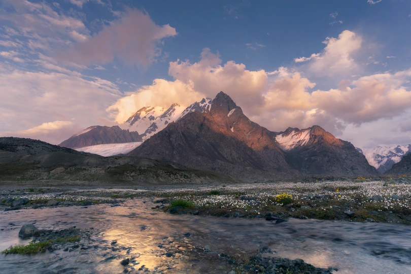 一条河流蜿蜒穿过山谷 背景是山脉和天空中的云朵。