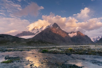 一条河流蜿蜒穿过山谷 背景是山脉和天空中的云朵。