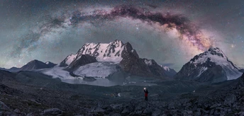 一个人站在白雪皑皑的山上 仰望着夜空中繁星闪烁的星空。