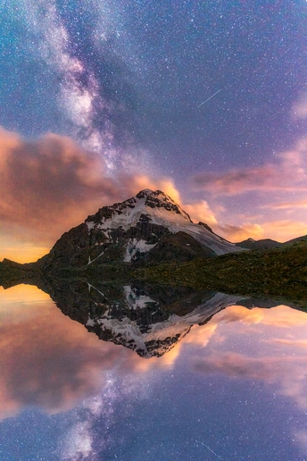 湖中倒影着一座山 天空中繁星闪烁 云彩飘荡。