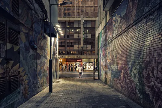夜晚城市里的一个巷子 人们沿着街道走 墙上涂鸦