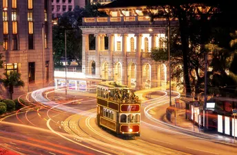 夜晚行驶在城市街道上的公交车 周围有高楼大厦。