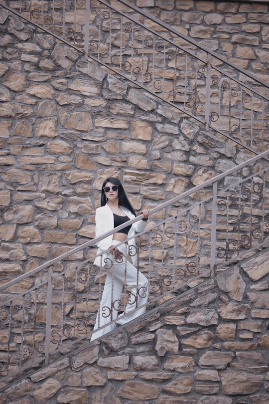 一位戴太阳镜的女人站在一块石头建筑物的台阶上