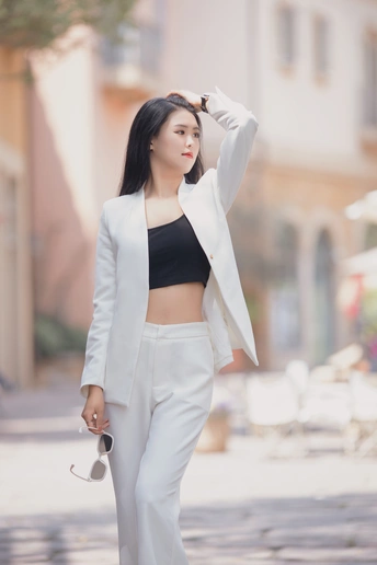 一位穿着黑色露脐上衣和白色裤子的女士在街上。