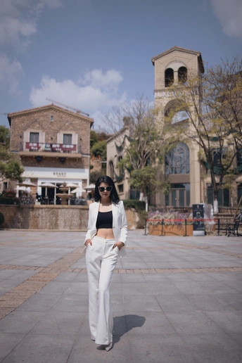 一位穿着白色裤子和黑色太阳镜的女人正在人行道上走