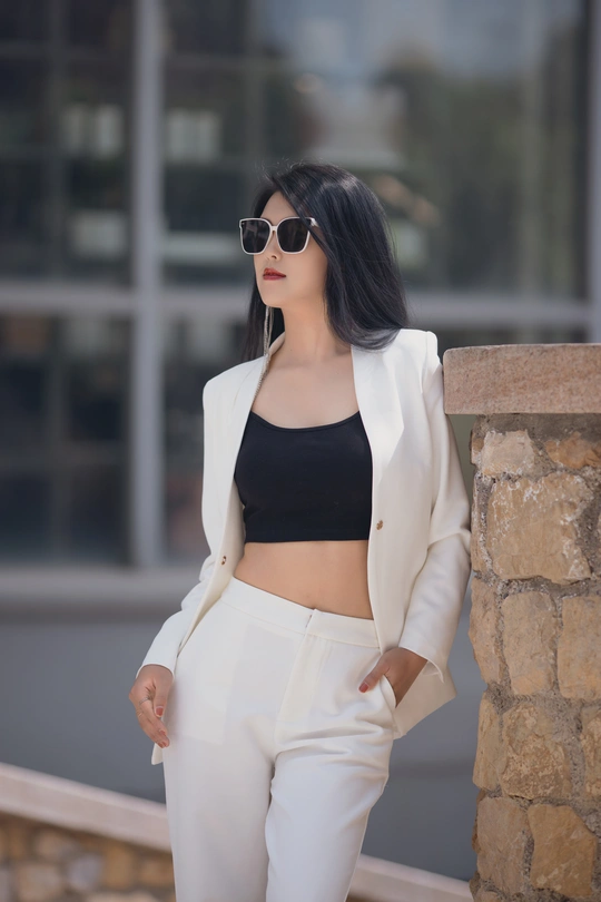 一位穿着黑色露脐上衣和白色裤子的女人