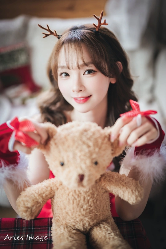 一位年轻女子抱着泰迪熊为圣诞照片摆姿势