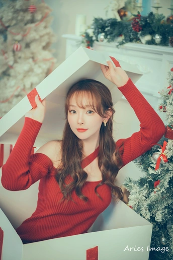 一位穿着红色毛衣的女人在圣诞树前用盒子顶在头上摆姿势