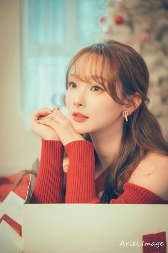 一个穿着红色毛衣的年轻女子坐在桌子旁 使用笔记本电脑。